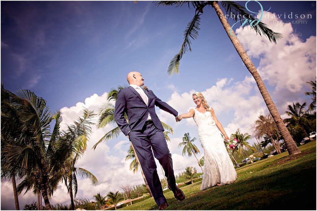 bride and groom in navy walk amongst coconut trees