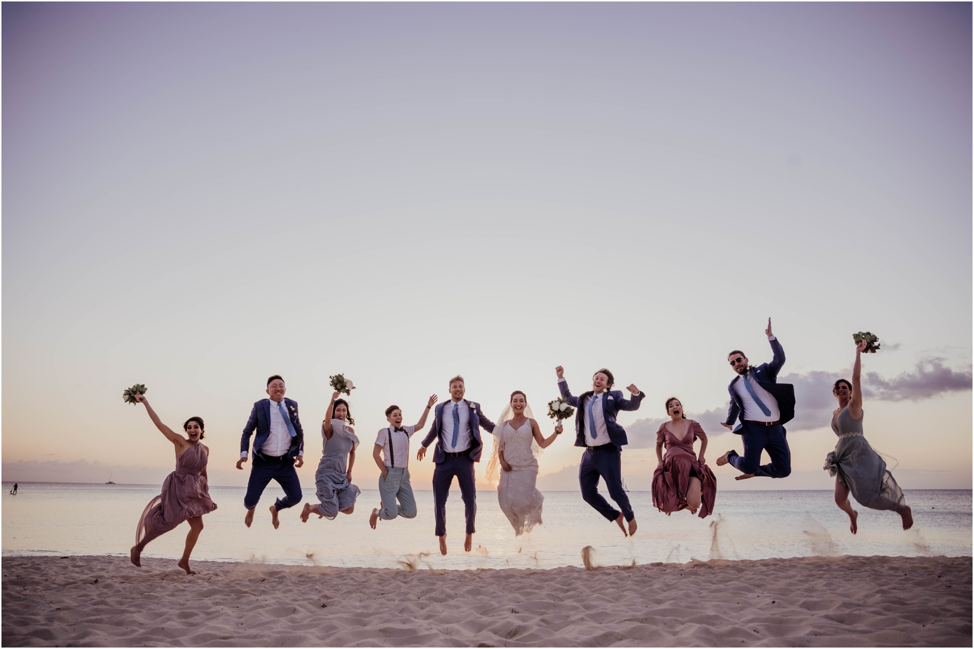 bridal party jumping in sand